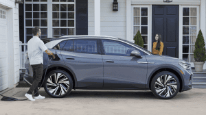 couple charging volks wagon electric vehicle infront of house